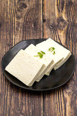 Sliced Feta cheese with herbs on wooden background. Close-up breakfast cheese