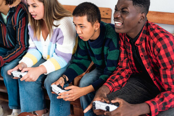 Young multiracial teenagers playing online video game console at home - Youth people addicted to...