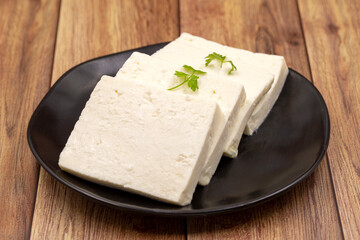 Sliced Feta cheese with herbs on wooden background. Close-up breakfast cheese