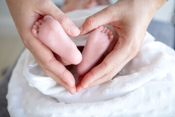 Purest love. A mother holding her baby girls tiny feet in her hands so that it forms a heart.
