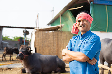 confidently standing happy smiling diary farmer at farm house with crossed arms by looking at...