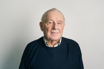 Senior man with gray hair and wrinkles near gray wall