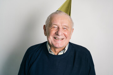 Cheerful elderly man in party hat in studio
