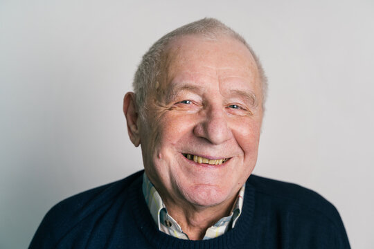 Senior Smiling Man With Gray Hair And Wrinkles Near Gray Wall