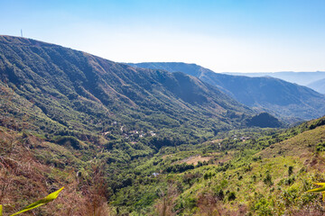 mountain range covered with dense green forests and bright blue sky at morning