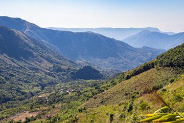 Fototapeta na wymiar mountain range covered with dense green forests and bright blue sky at morning