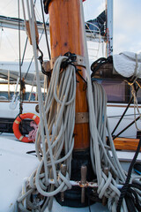Obraz premium Part of the mast of a sailing yacht, with multi-colored ropes for fastening and a winch mechanism.