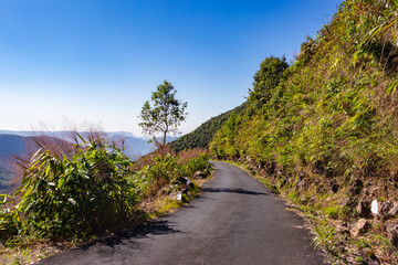 Fototapeta na wymiar isolated mountain tarmac road with forests and bright blue sky at morning