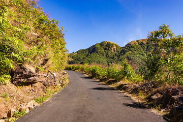 Fototapeta na wymiar isolated mountain tarmac road with forests and bright blue sky at morning