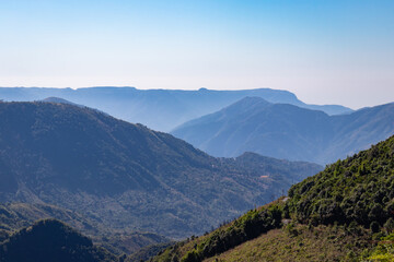 Fototapeta premium misty mountain range covered with forests and bright blue sky at morning