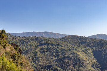 mountain covered with green forests and misty blue sky at morning from flat angle