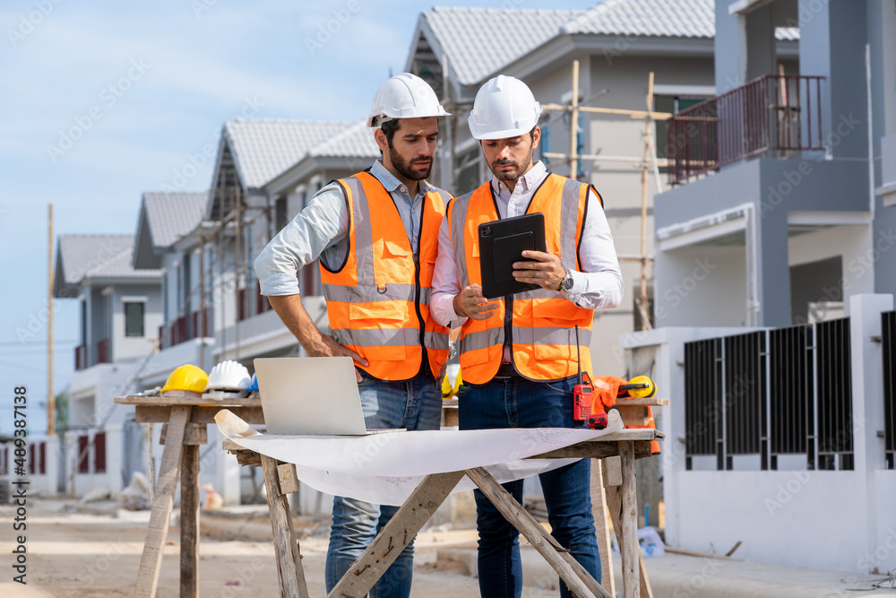 Poster engineer with foreman working on his blueprints with documents on construction site,meeting,discussi