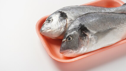 Raw fresh uncooked dorado or sea bream fish with lemon, herbs,  cherry tomatoes and spices on  black background