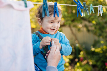 cute baby boy playing with clothespins and clothes