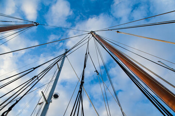 Obraz premium Masts of sailing yachts without sails with anchoring ropes. View from below.