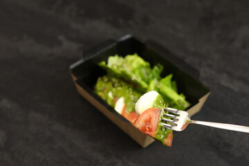 Fresh italian caprese salad with mozzarella and tomatoes with fork on dark background.