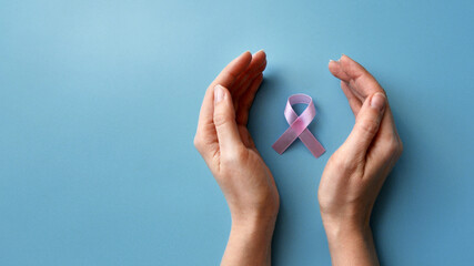 Pink ribbon in the hands of a woman. A symbol of the fight against breast cancer