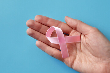 Pink ribbon in the hands of a woman. A symbol of the fight against breast cancer