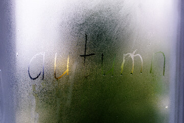 Foggy glass on window with written finger word Autumn. Concept photo with copy space