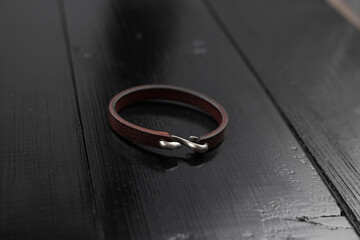 Brown leather male bracelet on the dark wooden desk