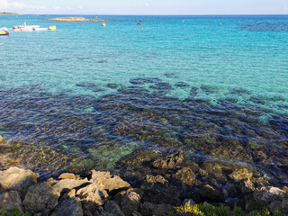 View of the clear water of the Mediterranean Sea, the pier on the Fig Tree Bay beach with a boat...