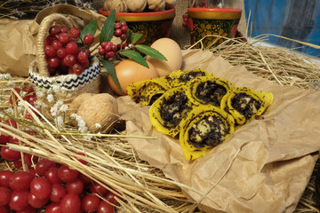 Pancakes, traditional Ukrainian slapjack with poppy seeds and walnuts. In red wooden utensils with Petrikovskaya painting. Craft eco paper. Maslenitsa, fried flapjack