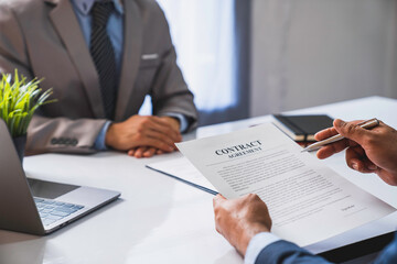 employer interviewing for a job or head of HR is reading a resume while discussing the job applicant's resume. An employer in a suit is interviewing for a job. Hire a Resource Manager and recruiting