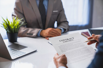 An employer interviewing for a job or head of HR is reading a resume while discussing the resume. An employer in a suit is interviewing for a job. Hire a Resource Manager and recruiting concept