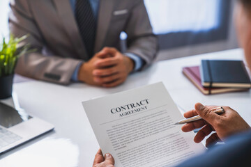 employer interviewing for a job or head of HR is reading a resume while discussing the job applicant's resume. An employer in a suit is interviewing for a job. Hire a Resource Manager and recruiting