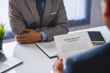 An employer interviewing for a job or head of HR is reading a resume while discussing the resume. An employer in a suit is interviewing for a job. Hire a Resource Manager and recruiting concept