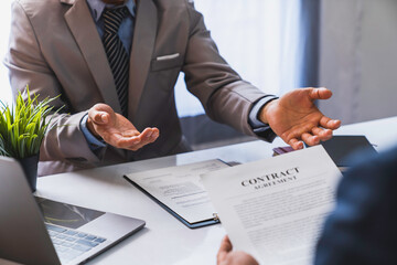 An employer interviewing for a job or head of HR is reading a resume while discussing the resume. An employer in a suit is interviewing for a job. Hire a Resource Manager and recruiting concept