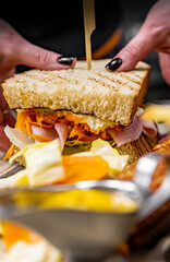 wooman hand cooking big sandwich with meat and vegetables on kitchen