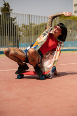 Una mujer caucásica con tatuajes y pelo corto en una pista deportiva con un skate