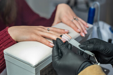 Fototapeta premium Close up of a young brunette trying to choose the right color of nail polish in a beauty salon