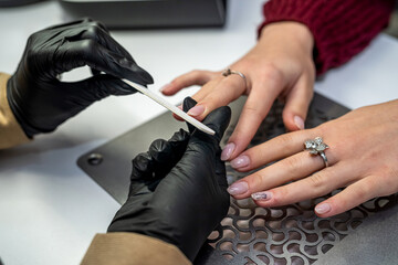 the manicurist  gloves holds the client's hand and works with it during the epidemic.