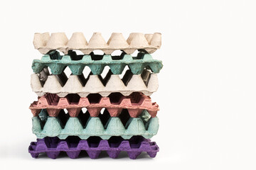 Caja contenedora de cartón de huevos de colores apiladas sobre un fondo blanco liso y aislado. Vista de frente. Copy space