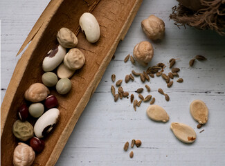 Assorted seeds on a whitewashed wooden table including bean, pea, pumpkin, anise, bald cypress 