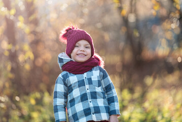 Portrait of a smiling little boy in a hat and scarf in autumn with copy space