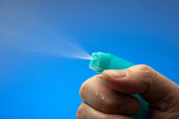Small spray bottle pulverizer nozzle macro held by Caucasian male hand. Close up studio shot,...