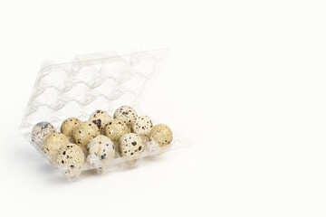 Huevos de codorniz dentro de una caja transparente de plástico sobre un fondo blanco liso y aislado. Vista de frente. Copy space