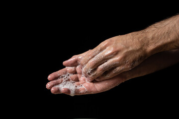 Fototapeta premium Washing hands with soap on a black background. Personal hygiene and health care.
