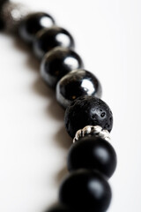 beads of  bracelet with black semipreciouse stones around white background. extreme macro shot