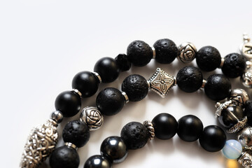 details  of  bracelet with black semipreciouse stones with natural lava, shungite,  hematite  around white background. macro shot . top view