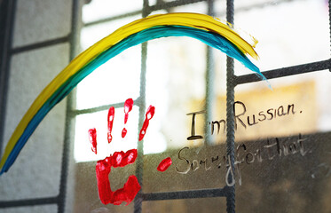 On the window is painted Ukrainian flag and blood hand where is written I am Russian, sorry for that. Concept of new protest move