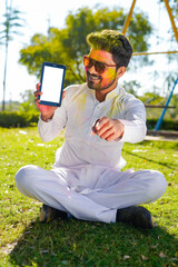 Portrait of indian happy young man on holi color festival using mobile phone