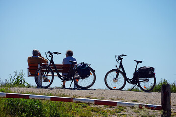 Rentnerpaar mit E-Bikes erolt sich am Meer