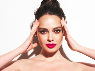 Fototapeta premium Fashion beauty portrait of young brunette woman with evening stylish makeup and perfect clean skin. Sexy model with hair in a bun posing in studio. With pink bright natural lips. Isolated on white
