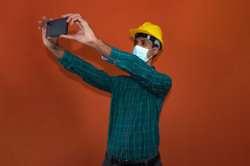 Engineer, architect or worker with yellow helmet and pandemic mask isolated on white background. Engeneer at work talking on the cell phone.