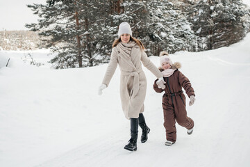 Fototapeta na wymiar mother and daughter have fun running in the snowy forest