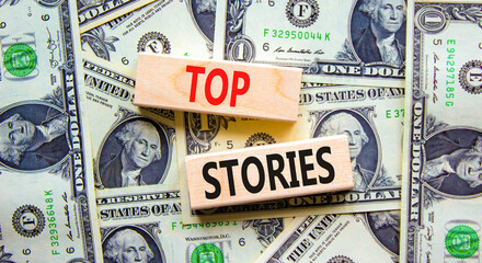 Fototapeta na wymiar Top stories symbol. Concept words Top stories on wooden blocks on a beautiful background from dollar bills. Business story and top stories concept, copy space.